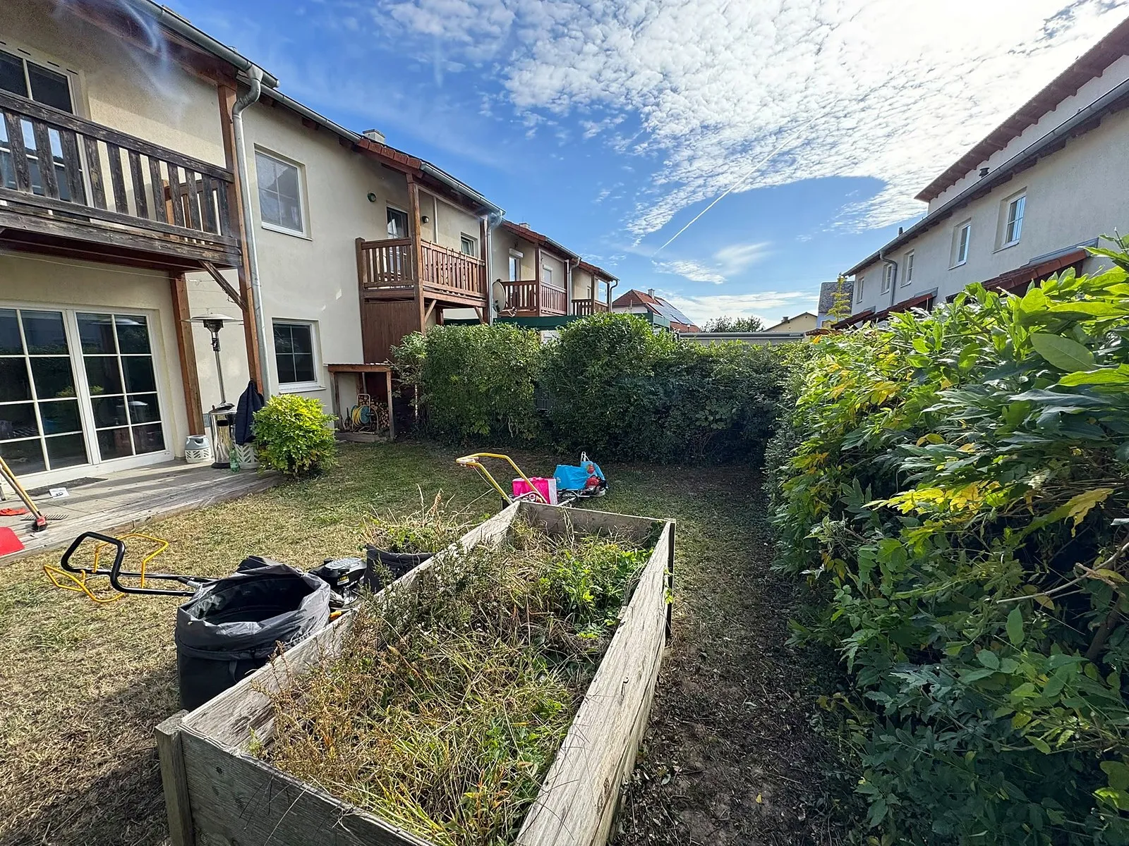 Garden after: lawn mown, lawnmower and garden bags by the raised bed, on the left the terrace under the balcony